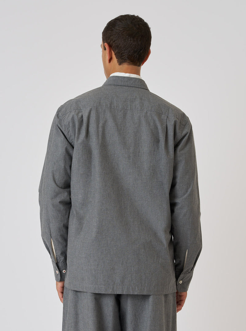 Back view of a model wearing the Charcoal Organic Chambray Lucky Shirt. The shirt is a relaxed fit and made of a textured charcoal fabric. Simple white studio background.