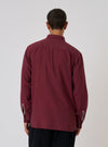 Back view of a model wearing the Red Brushed Marl Twill Square Pocket Shirt. The shirt is a deep red color and made of a textured twill material. Shot against a plain white backdrop.