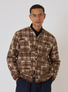 A model poses against a white backdrop wearing the Sand Patch Check Fleece Cardigan. The cardigan features a brown and beige check pattern and a relaxed fit.