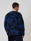 A man stands in front of a white background, modeling the Blue Flower Fleece Zip Liner Jacket. The jacket features a blue and black floral pattern.