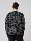 Back view of a model wearing a Charcoal Flower Fleece Zip Liner Jacket. The jacket has a black and gray floral pattern. Shot against a white background.