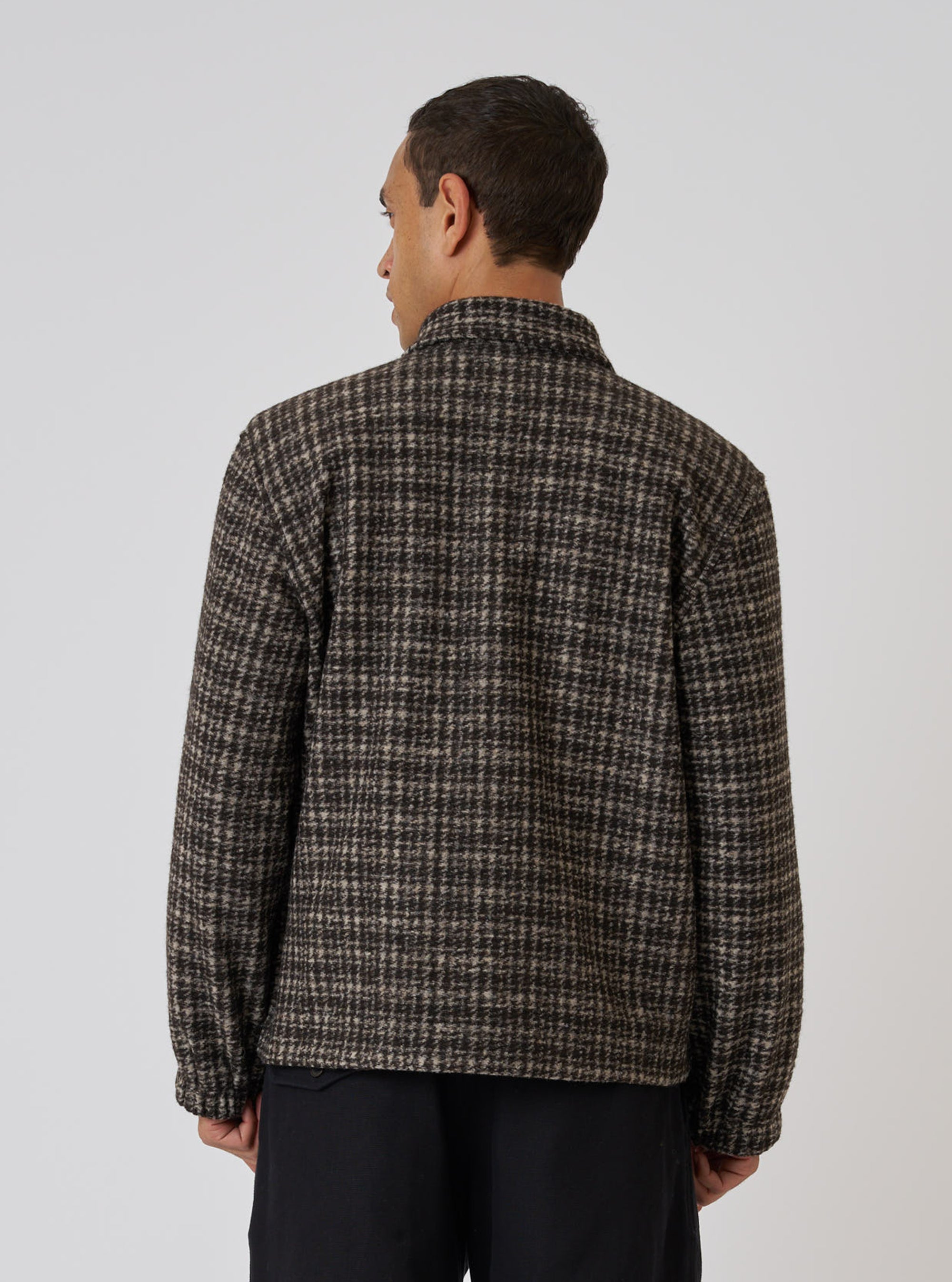 Back view of a model wearing a Brown Jacquard Knit Rams Jacket. The jacket has a brown and beige grid pattern. Shot against a plain white background.