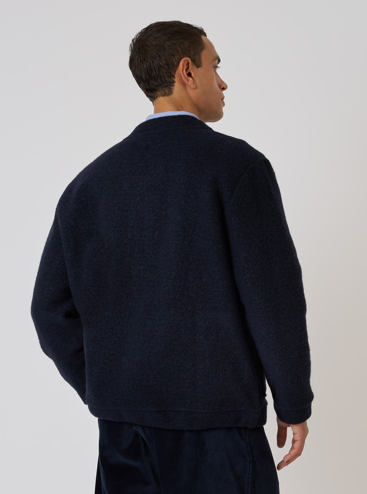 A man poses in the Navy Wool Fleece Advance Cardigan against a plain background. The cardigan is a deep navy color and appears soft and warm.