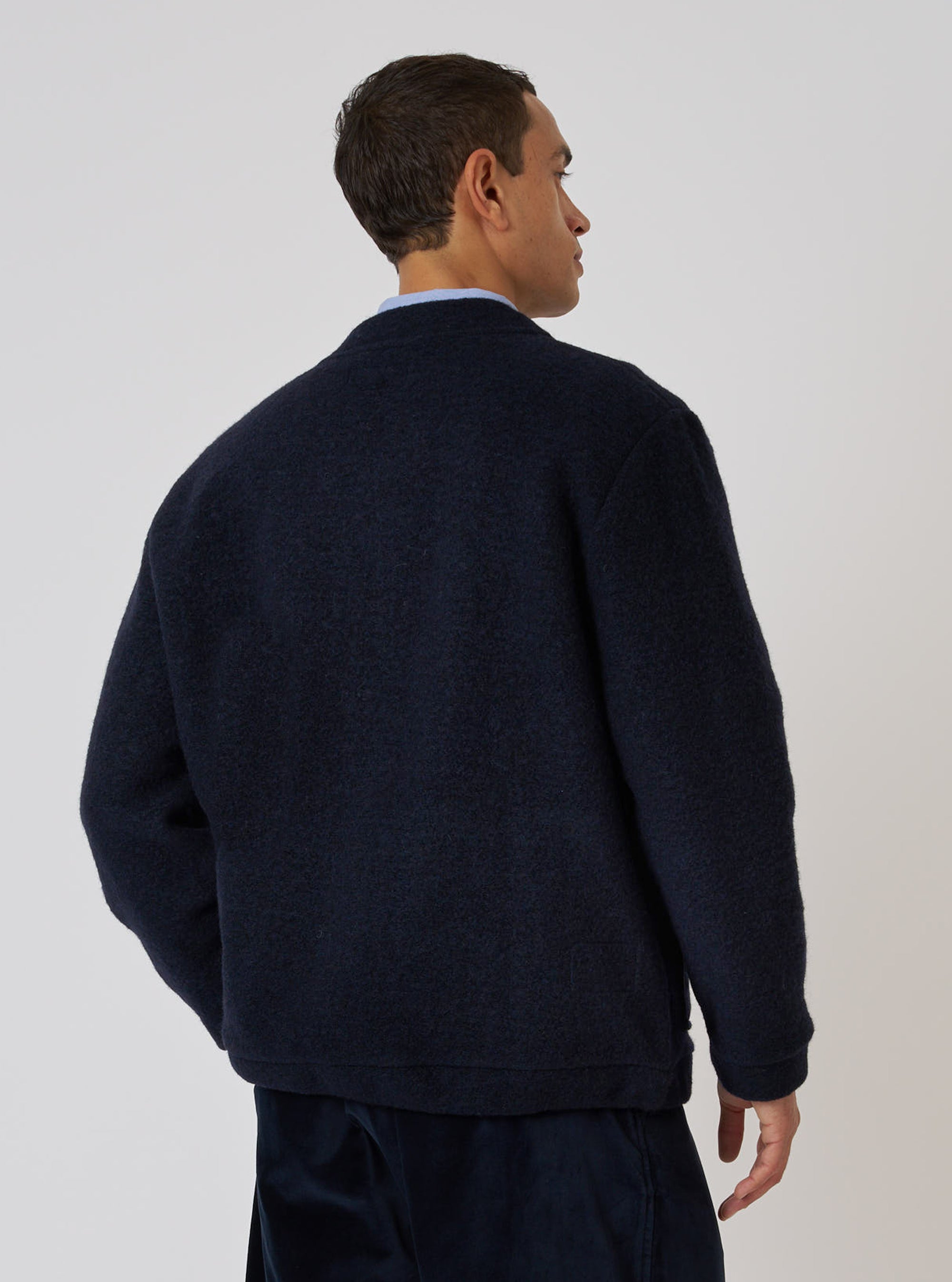 A man poses in the Navy Wool Fleece Advance Cardigan against a plain background. The cardigan is a deep navy color and appears soft and warm.