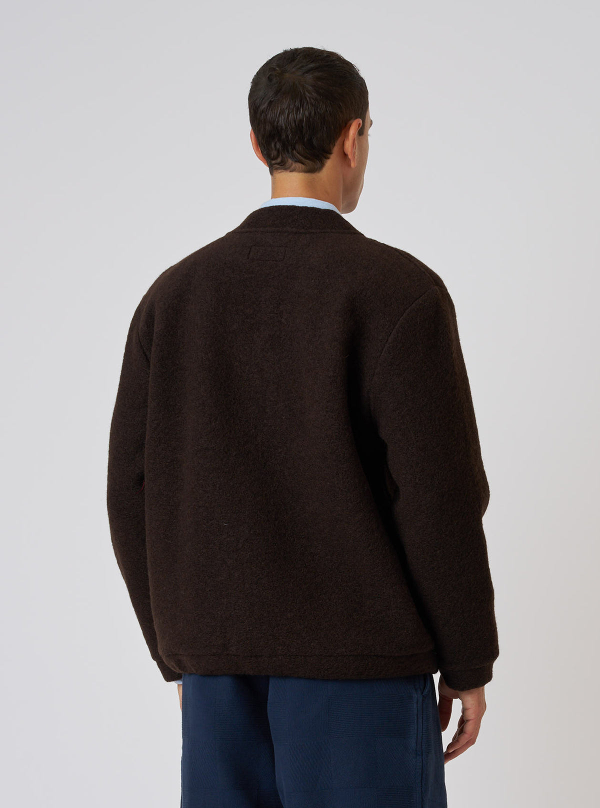 Back view of a model wearing a Brown Wool Fleece Advance Cardigan. The cardigan is a relaxed fit. Shot against a plain white background.