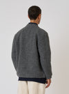 Back view of a model wearing the Grey Marl Wool Fleece Advance Cardigan. The fleece is layered over a navy shirt and paired with cream pants. Shot against a plain white backdrop.