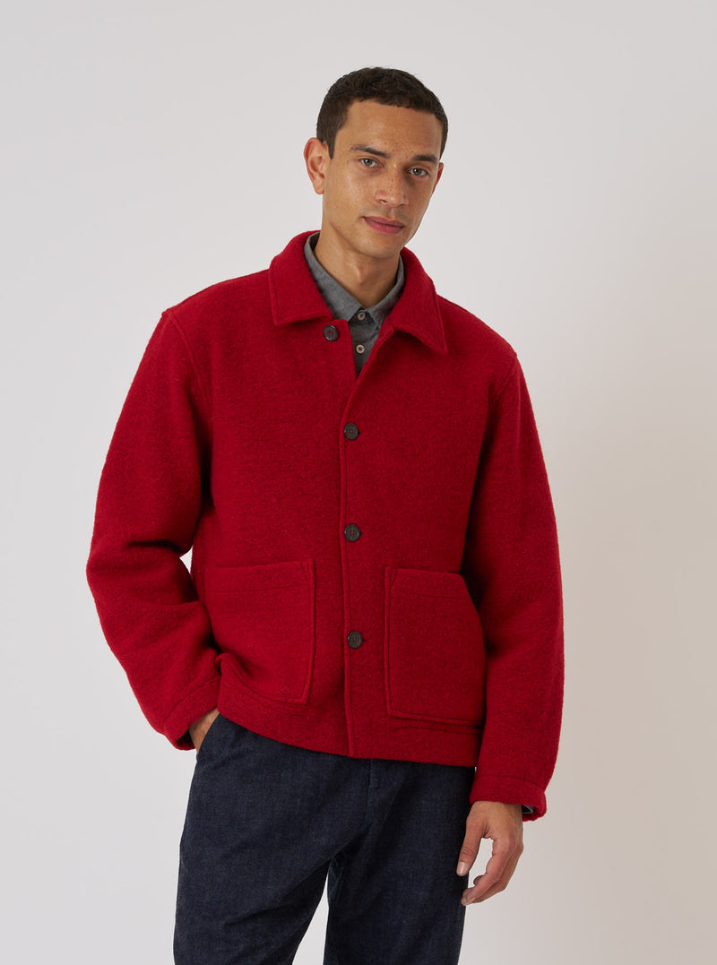 A man models the Red Wool Fleece Rams Jacket against a plain backdrop. The jacket is a vibrant red with a classic fit and visible wool texture.