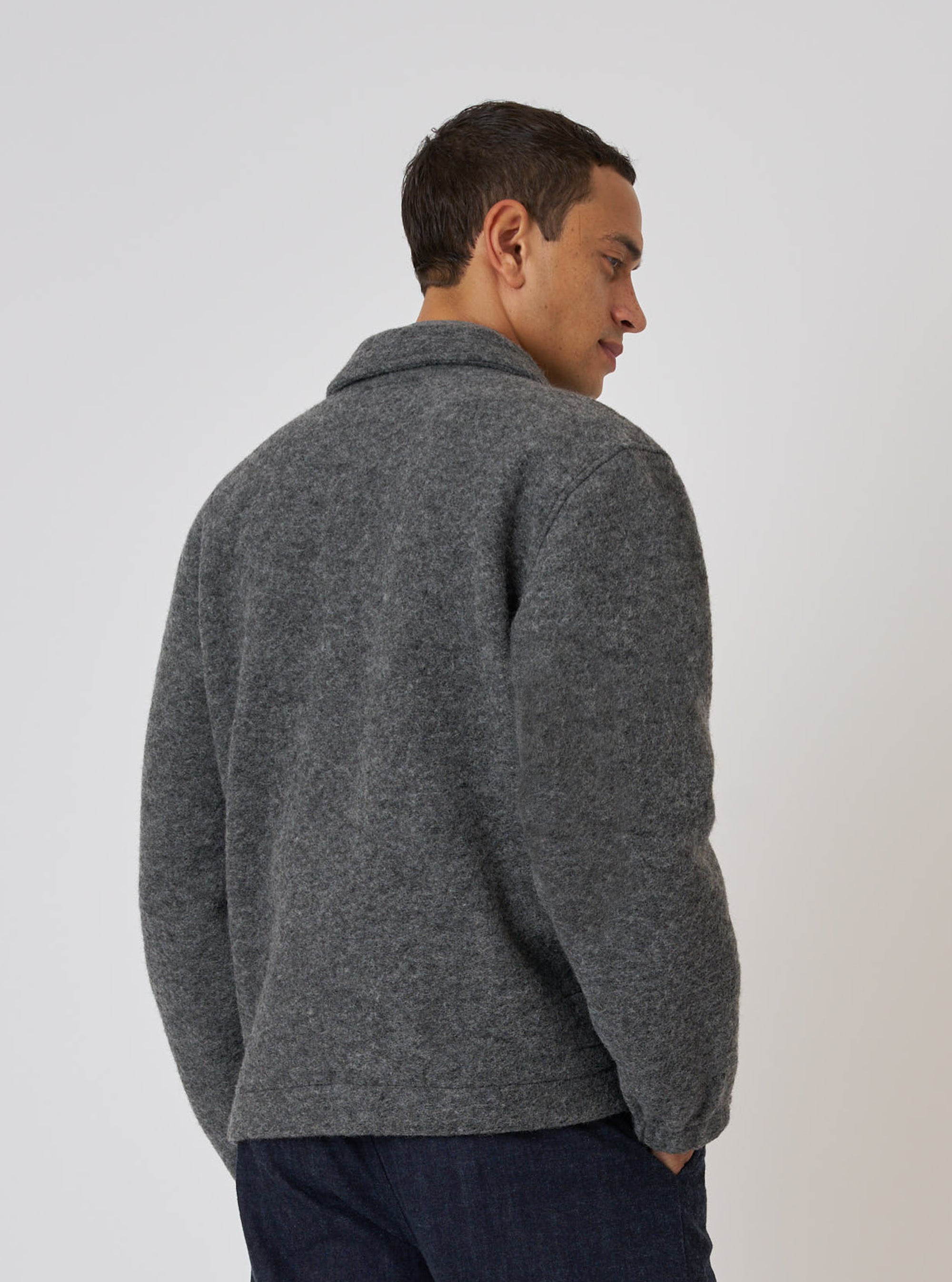 A man models the Grey Marl Wool Fleece Rams Jacket against a plain white background. The jacket is a grey wool fleece. The man is wearing dark jeans.