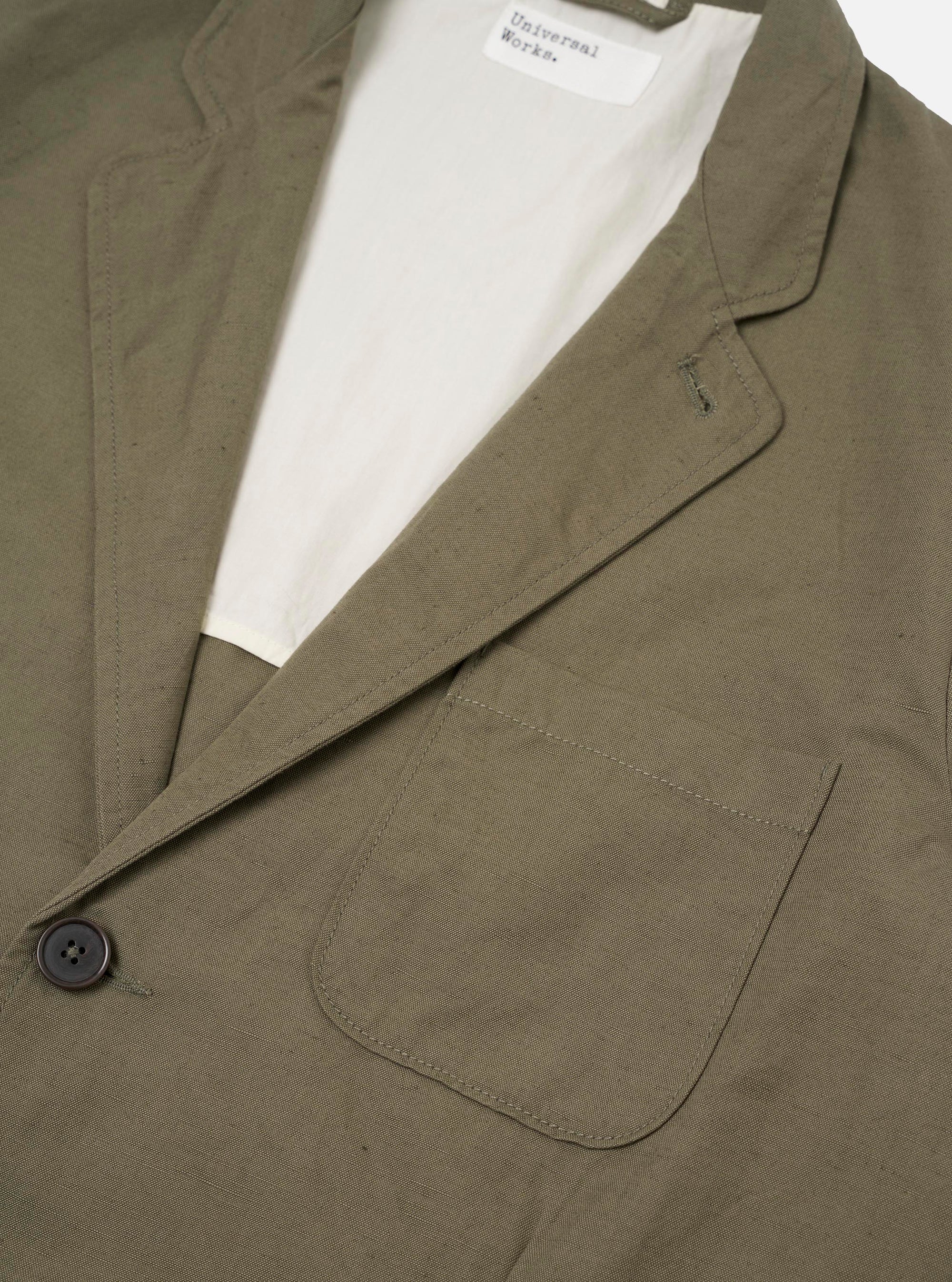 The Olive Linen Slub Weave Two Button Jacket is shown from the back as a flat lay against a plain white background. The image highlights the jacket's structured shoulders, clean rear seams, and a single vent at the hem. The fabric has a visible slubby texture in an olive green hue.