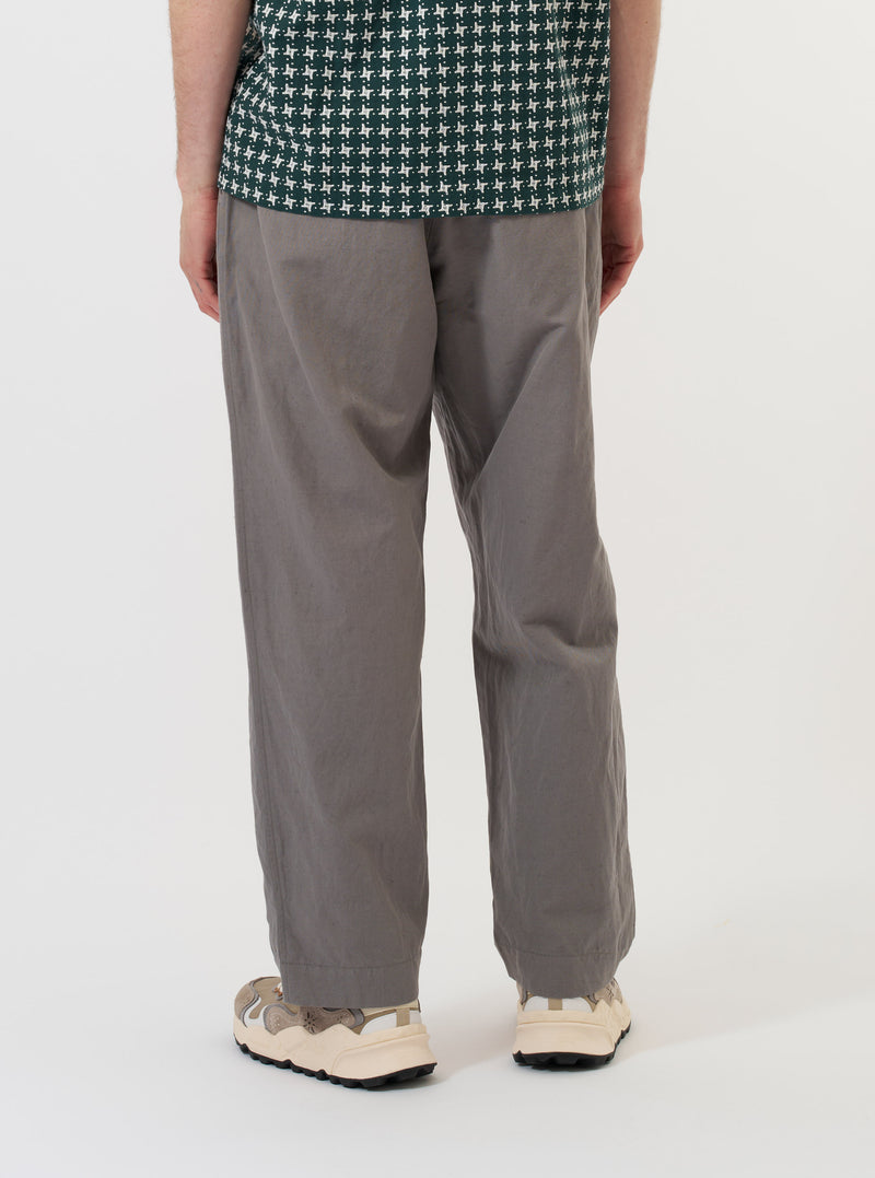 A model is wearing the Mid Grey Linen Slub Weave Oxford Pant against a plain white background. The image, captured from the rear, highlights the loose, wide-leg fit of the grey trousers, showing the elasticated waistband and one of the back pockets. No other garments are visible.