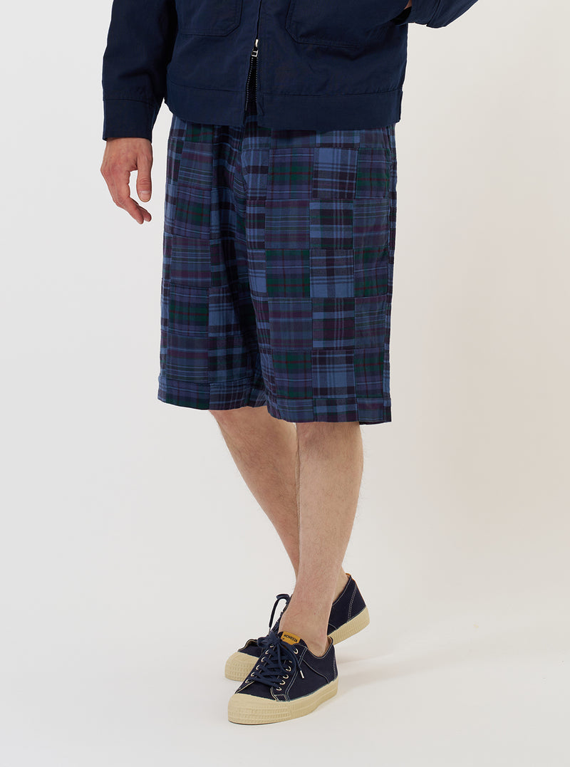 Person wearing blue plaid shorts and navy shoes on a white background
