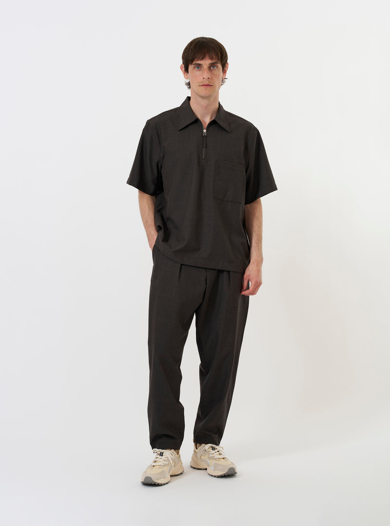 The Brown Marl Tropical Suiting Ewan Shirt is shown laid flat against a plain white background. The garment features a half-zip front, a classic pointed collar, a straight hem, and a single chest pocket on the left side. The fabric has a fine, textured brown marl finish.