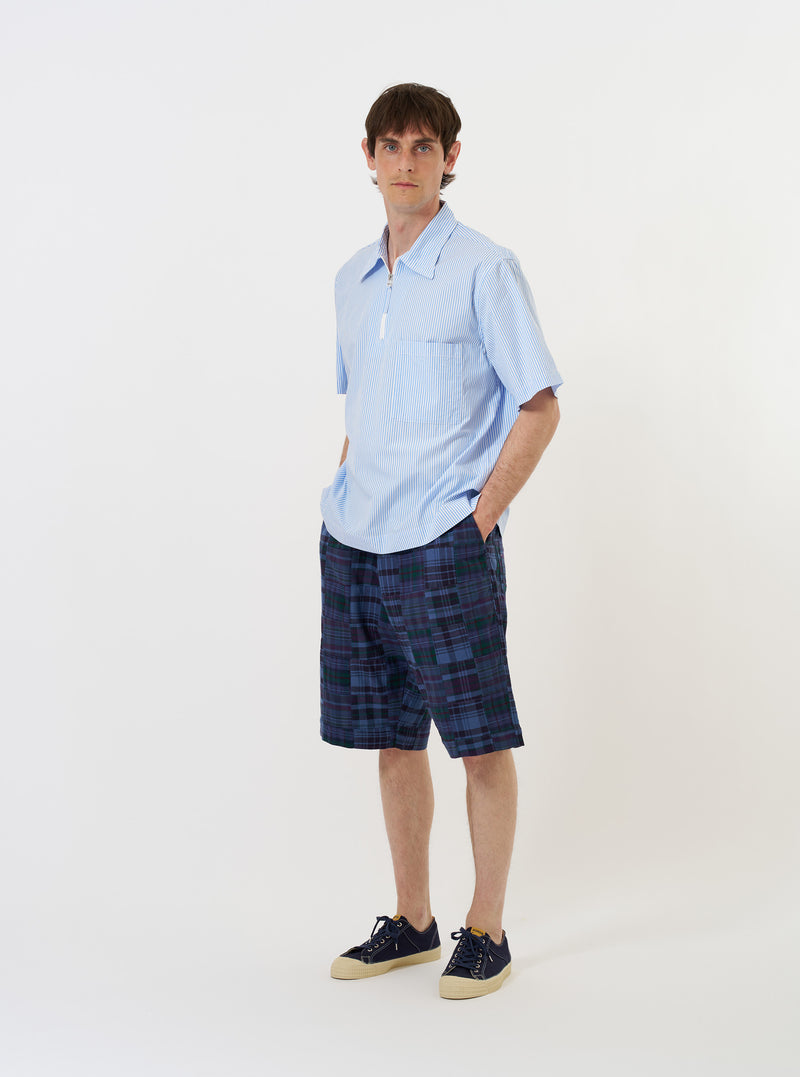 The Sky/White Classic Nipon Stripe Ewan Shirt is shown laid flat against a solid white background. The garment features a light blue and white vertical stripe pattern, a half-zip front opening, a classic pointed collar, and a single chest pocket on the left side. The short sleeves and straight hem are clearly visible.