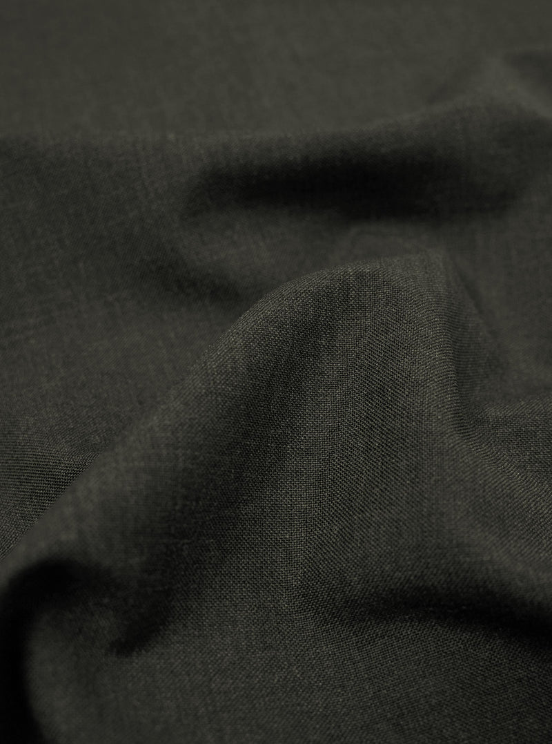 A close-up fabric swatch of the Olive Marl Tropical Suiting material used for the Two Button Jacket shows a detailed weave with a blend of green and grey tones. The image highlights the smooth, professional texture of the polyester-wool fabric.