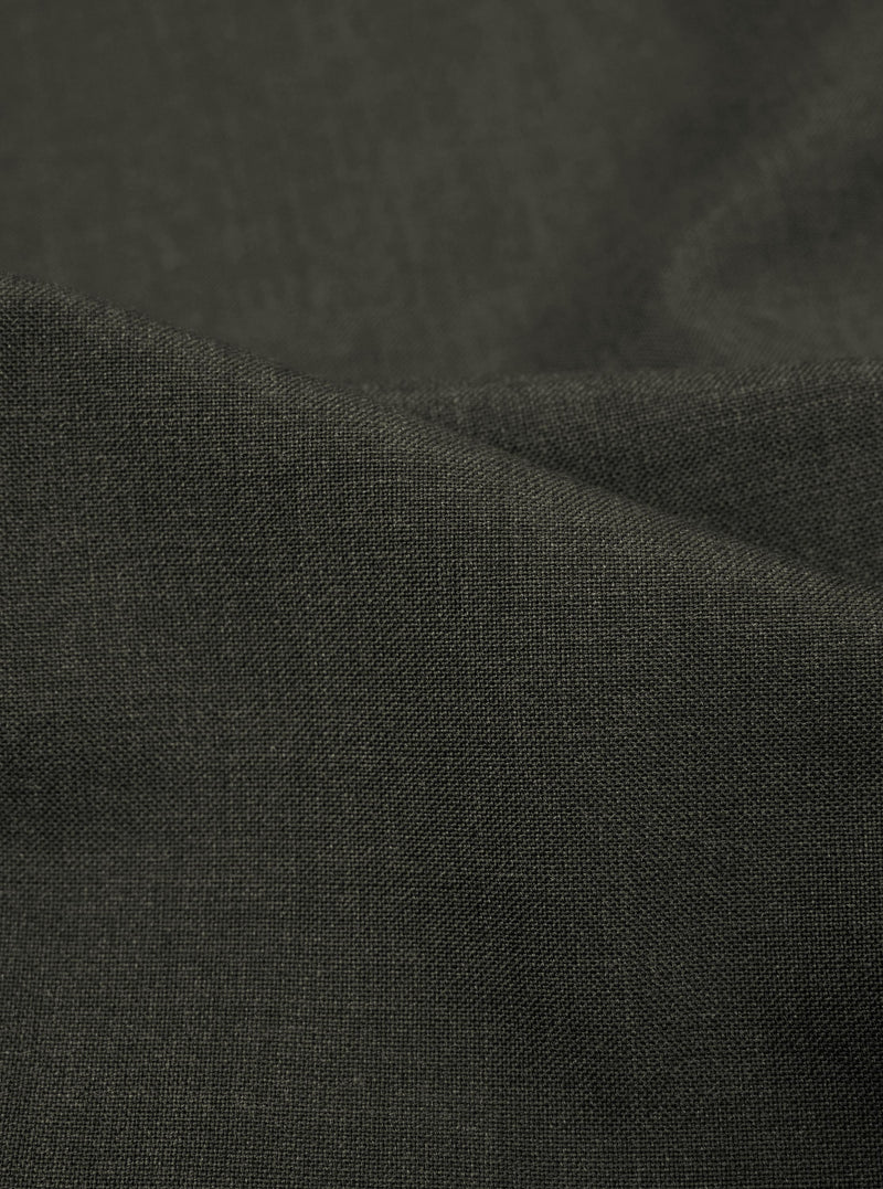 A detailed, close-up fabric swatch of the Olive Marl Tropical Suiting Pleated Track Pant shows the fine, textured weave of the olive green material.