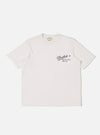 The Paraboot x Universal Works Ecru Single Jersey Print Tee is shown as a flat lay against a white background. The short-sleeve t-shirt features a ribbed crew neck and a prominent black graphic print on the left chest, which includes a script logo and block typography. The fabric is a solid ecru cotton with a smooth finish.