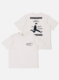 The Paraboot x Universal Works Ecru Single Jersey Print Tee is shown from both the front and back as a flat lay against a white background. The front of the ecru T-shirt features a small graphic on the left chest, while the back displays a large, colorful vintage-style illustration of a person walking a dog. The garment has a ribbed crew neckline and short sleeves.