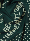 A close-up fabric swatch of the Paraboot x Universal Works Green Cambric Neckerchief highlights the solid green color and the fine, smooth weave of the cambric cotton material. The fabric fills the frame, providing a detailed view of its texture.