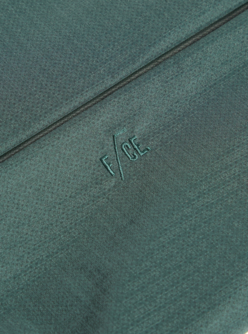 Close-up of the F/CE.® Green Nylon 2.5 Layer Sacoche showing the fabric texture and embroidered logo. The background is a simple, neutral surface.