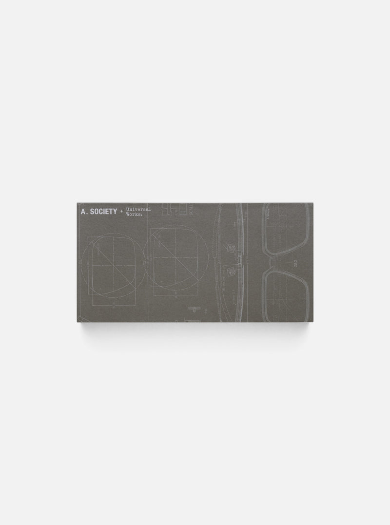 Close-up of the A. SOCIETY x Universal Works Brown Stanley Sunglasses box. The box is brown with a blueprint design of the sunglasses on it. 