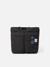 The Topologie x Universal Works Black UW Tech Helmet Bag on a white background. The bag is black and has several patches on it.