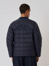 Back view of a model wearing the TAION x Universal Works Reversible Dark Navy Military Line Liner Jacket. The quilted jacket has 'PEACE LOVE & SOUL' embroidered on the back. Clean white background.