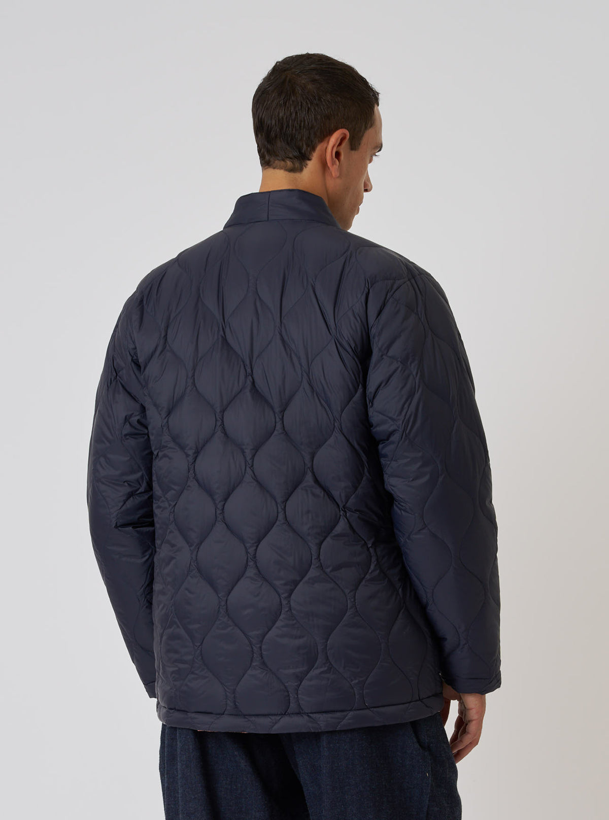 Back view of a model wearing the TAION x Universal Works Reversible Dark Navy Military Line Kyoto Work Jacket. The quilted jacket is on a white background.