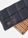 Close-up of the TAION x Universal Works Reversible Dark Navy Military Line Neck Warmer. Features a quilted dark navy side and a brown houndstooth patterned side with blue snap buttons.