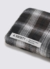 Close-up of the A. SOCIETY x Universal Works Brown Stanley Sunglasses case. Brown and white plaid fabric. The product tag is visible. Shot on a white background.