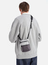 Back view of a model wearing the F/CE.® White Nylon Cordura Sil Portrait bag. The bag is gray and black with a black strap. Shot against a white background.