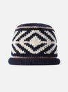 Detailed close-up view of the cableami® Navy Wool Jacquard Watch Cap laid flat on a plain white background, showcasing the jacquard pattern, crown shaping, and dark navy wool construction.