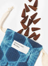 Harvest Incense Cones spilling from a blue tie-dye bag with cream-colored drawstrings on a white background. The incense cones are brown and cone-shaped. 