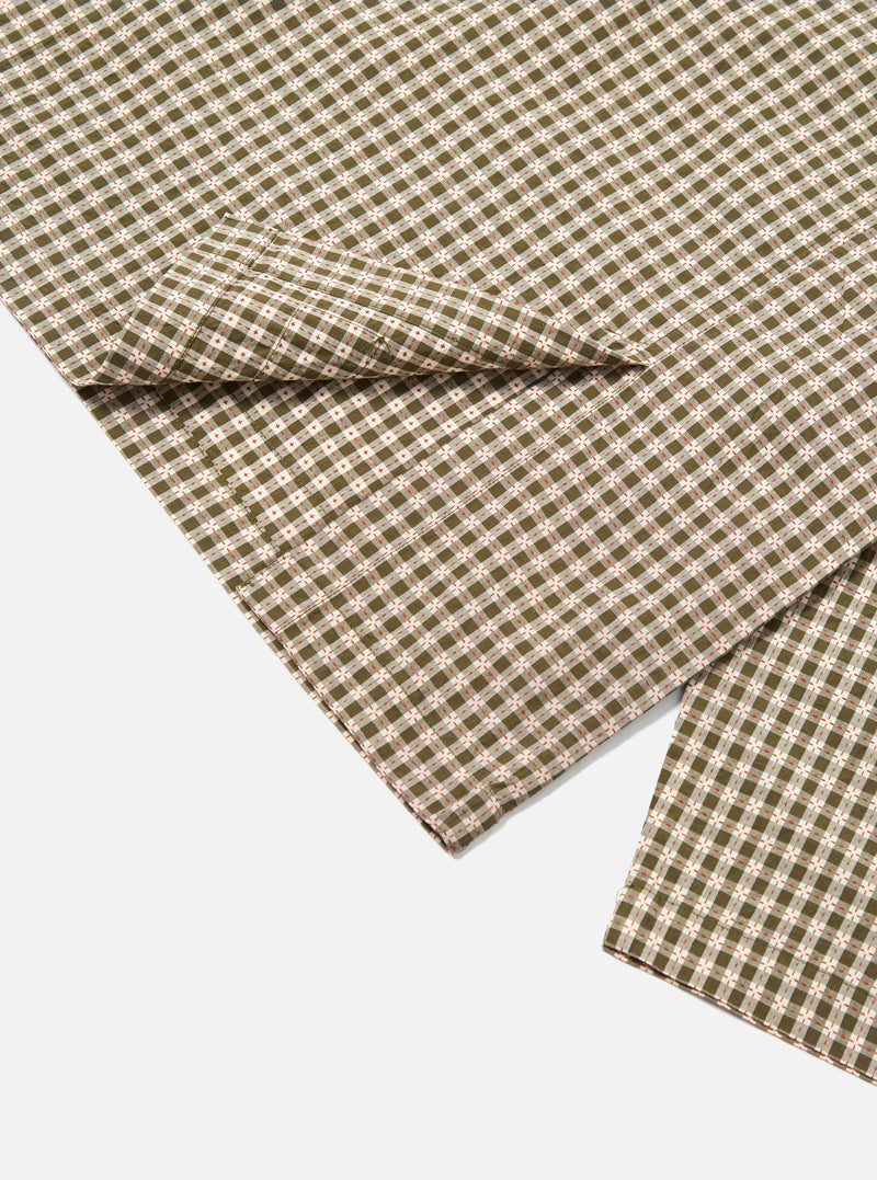 Close-up of the Olive Dobby Check Cancun Jacket fabric. The jacket has a green and white check pattern with red accents, laid on a white surface.