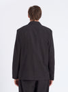 Back view of a model wearing a Charcoal Fine Linen Mix Three Button Jacket. The jacket is on a white background, showcasing its fit and material.