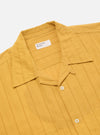 Close-up of the Mustard Dobby Self Stripe Camper Shirt on a white background. The shirt is mustard-colored with a dobby self-stripe pattern. It has a camp collar and short sleeves.