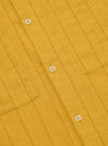 Close-up of the Mustard Dobby Self Stripe Camper Shirt. The shirt is a golden yellow with a subtle striped texture and white buttons. The background is a plain white surface.