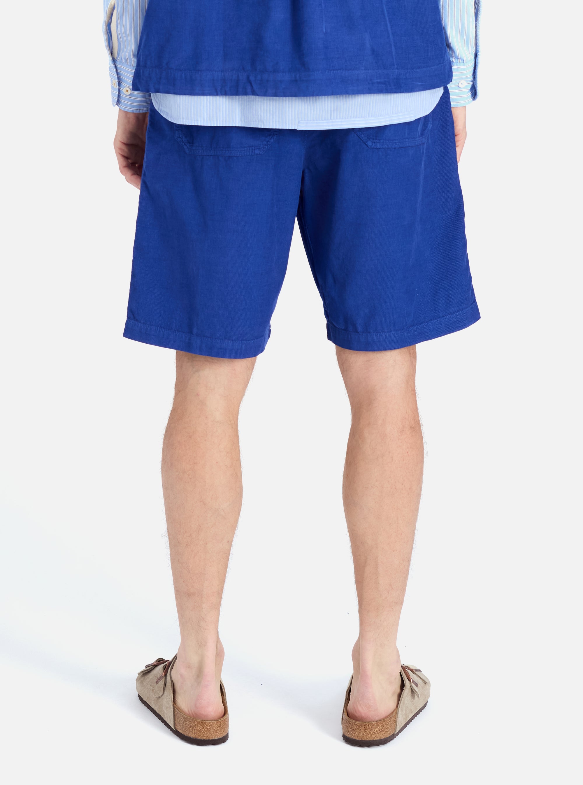 Back view of a model wearing the Work Blue Summer Cord Alva Short, made of blue corduroy. The image is shot on a white background.