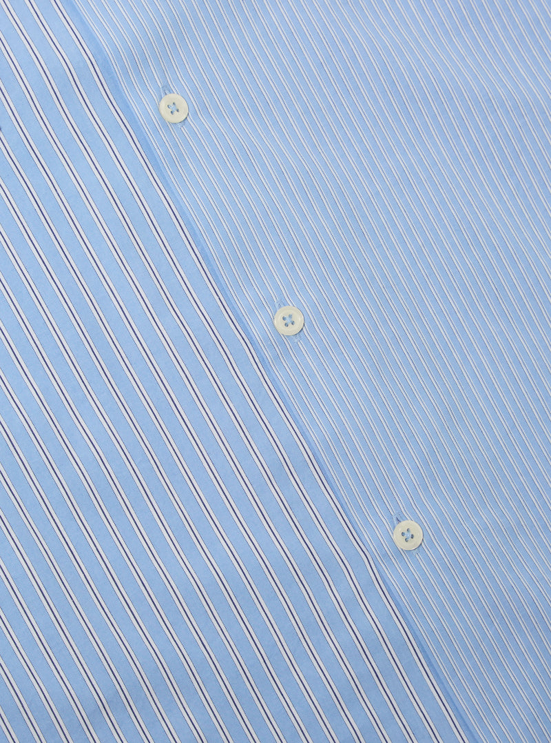 Close-up of the Blue Vila Stripes Sal Road Shirt, showcasing its light blue fabric with white and navy stripes and button details. The shirt is laid flat on a neutral surface.