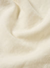 Close-up of the ecru linen cotton shirting Travail Overshirt fabric. The light-colored material shows subtle texture and soft folds, highlighting the blend of linen and cotton.
