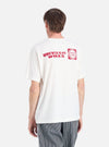 Back view of a model wearing an Ecru/Red Single Jersey Print Pocket Tee. The tee has a red print on the back. Shot against a white background.