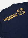 Close-up of the back of a Navy/Yellow Single Jersey Print Pocket Tee. The tee is navy with yellow print. The background is a plain white surface.