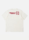 The Ecru/Red Single Jersey Print Pocket Tee is displayed on a white background. The tee is ecru with a red print on the back. The fit is relaxed.