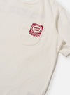 Close-up of the Ecru/Red Single Jersey Print Pocket Tee on a white surface. The tee features a red print on the pocket. The fabric is soft and the fit is relaxed.