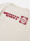 Close-up of the back of an Ecru/Red Single Jersey Print Pocket Tee. The ecru tee features a red print. The background is a plain white surface.