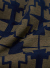 Close-up of the Navy/Mud Mitla Print Jersey Newlyn Polo fabric. The jersey material features a navy geometric print on a mud-colored background, showcasing the texture and pattern.