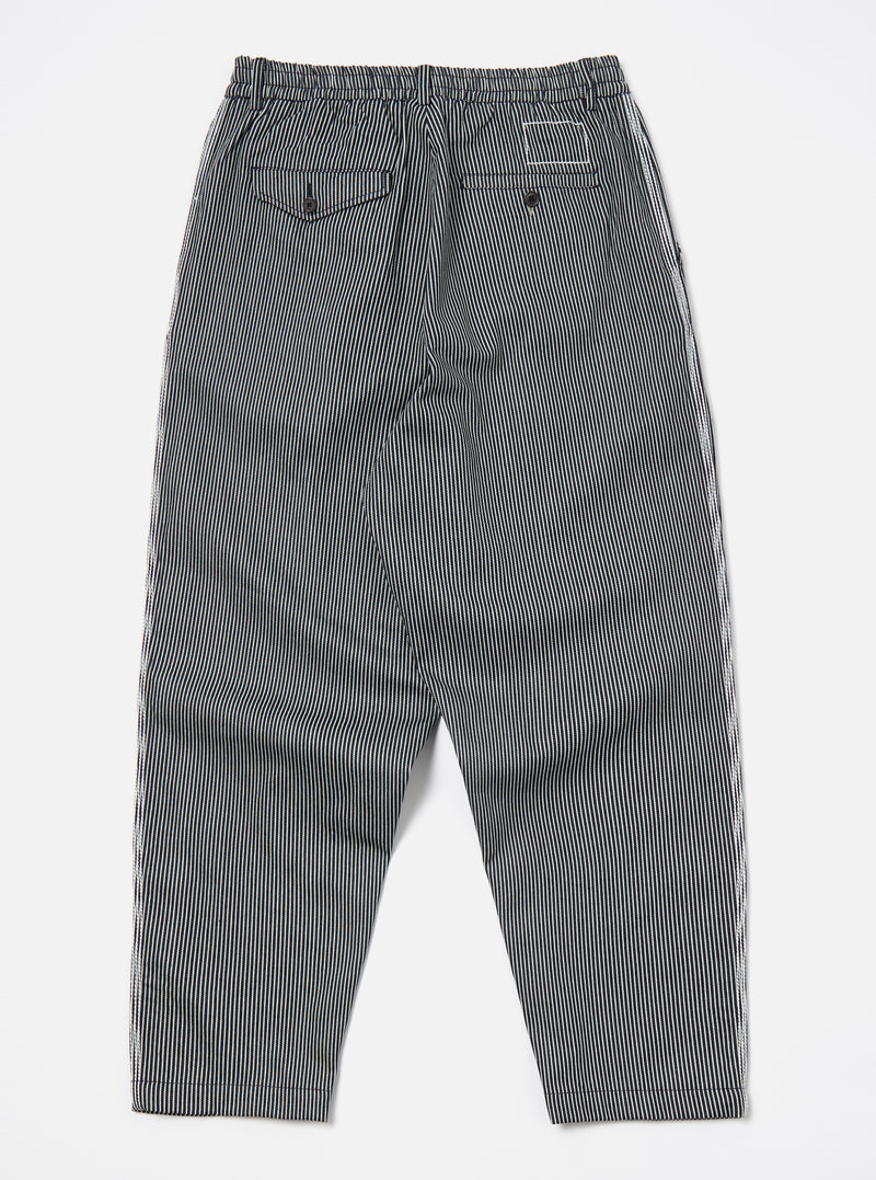 Back view of Indigo Hickory Stripe Denim Pleated Track Pant on a white surface. The pants have a relaxed fit and feature a striped pattern.