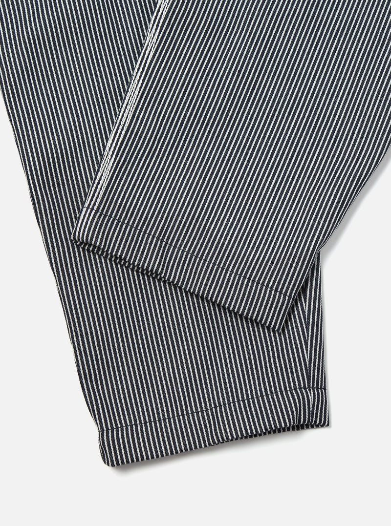 Close-up of the Indigo Hickory Stripe Denim Pleated Track Pant on a white surface, showcasing the fabric's texture and pleated design.