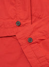 Close-up of the Orange British Wax Cotton Boston Parka showing the texture of the fabric, button details, and stitching. The image is taken on a flat surface.