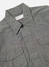 Close-up of the Charcoal Organic Chambray Parachute Field Jacket on a white surface. The jacket is charcoal gray and made of chambray fabric. It features a button closure and two front pockets.