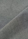 Close-up of the Charcoal Organic Chambray Parachute Liner Jacket fabric. The charcoal material is folded, showing the texture. The background is a plain white surface.